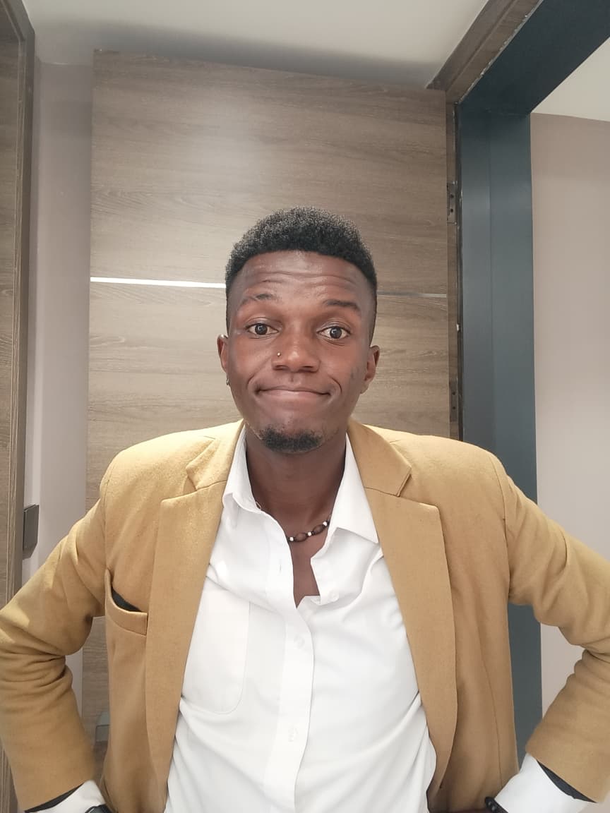 Lewis Muturi wearing a tan blazer